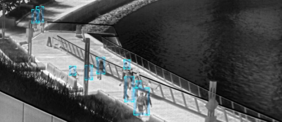 Thermal imagery cameras capturing images of people walking in a public setting and outlining them in a blue square.