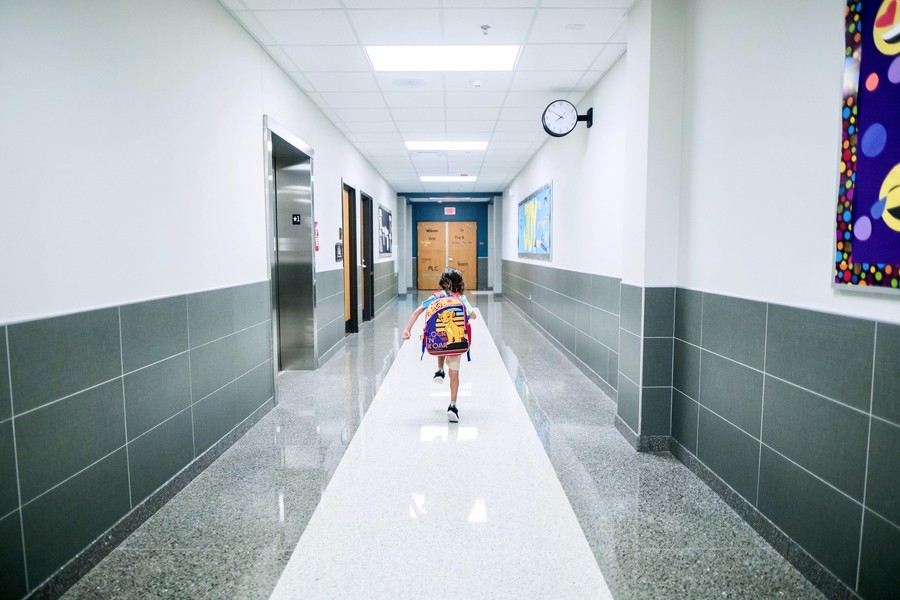  A child running along a school hallway. 