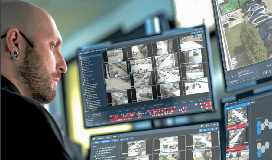 a man monitoring multiple security feeds on a desk